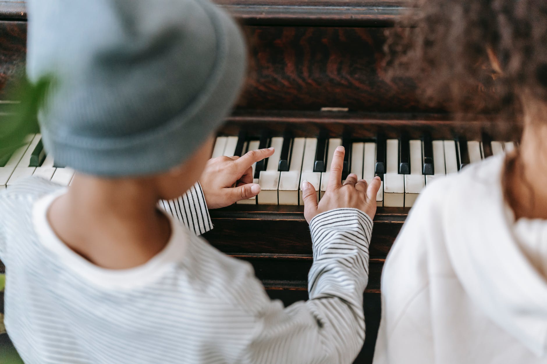 unrecognizable ethnic children playing piano at home